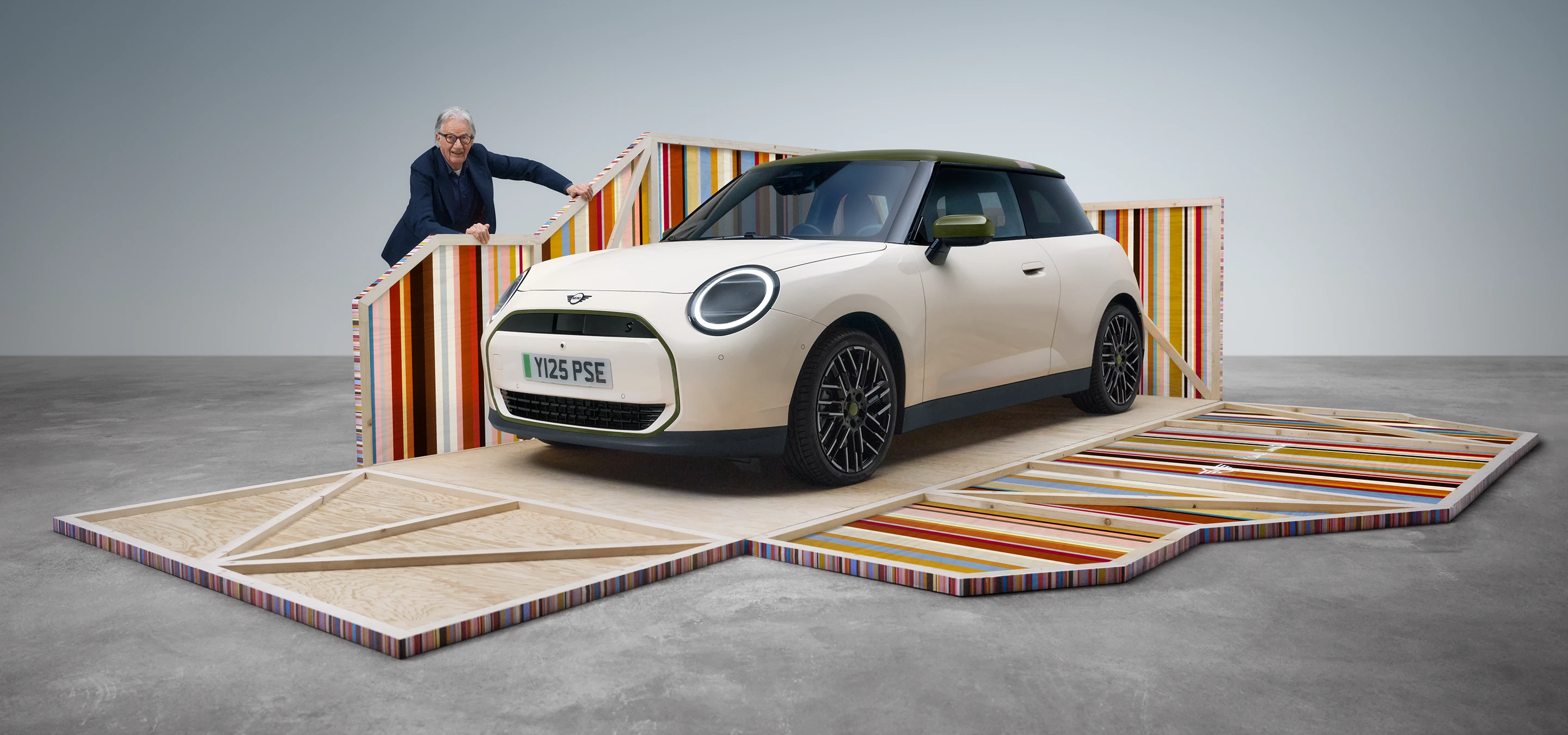 Front side view of the all-electric MINI Cooper Paul Smith Edition in Inspired White with designer Paul Smith